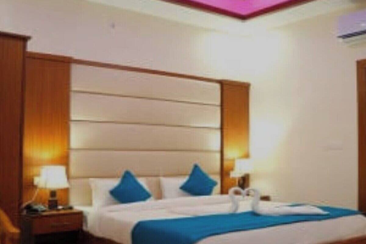 A hotel room with a large bed, two bedside tables, a nightstand, and a wall-mounted lamp.