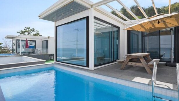 A modern pool area with glass walls, a wooden table, and a covered seating area. - Space Yeongdeok (Yeongdeok)
