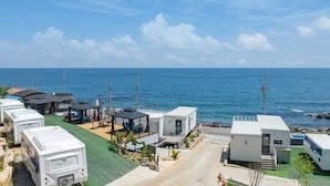 A coastal RV park with multiple RVs and mobile homes, a paved road, and a view of the ocean. - Space Yeongdeok (Yeongdeok)