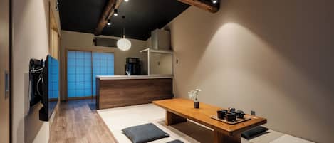 A modern interior with a wooden dining table, black cushions, and a traditional Japanese sliding door in the background.