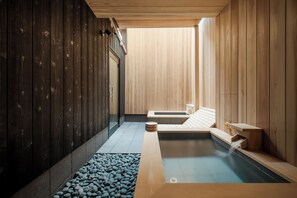 A modern spa with wooden walls, a hot tub, and a pebble-lined floor. - MACHIYA de SAUNA (Kyoto)