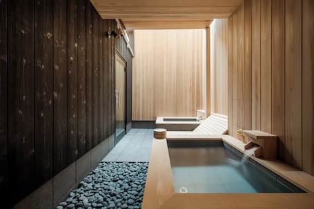 A modern spa with wooden walls, a hot tub, and a pebble-lined floor.