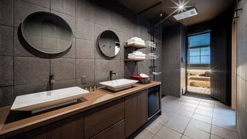 A modern bathroom with two sinks, a large mirror, and a shower area.