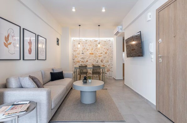 A modern living room with a sofa, a round coffee table, and a stone wall.