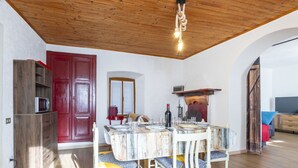 Un coin repas avec un plafond en bois, une porte rouge et une table dressée pour quatre personnes.