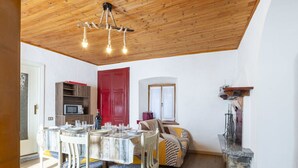 Un coin repas avec un plafond en bois, une porte rouge et une cheminée en pierre.