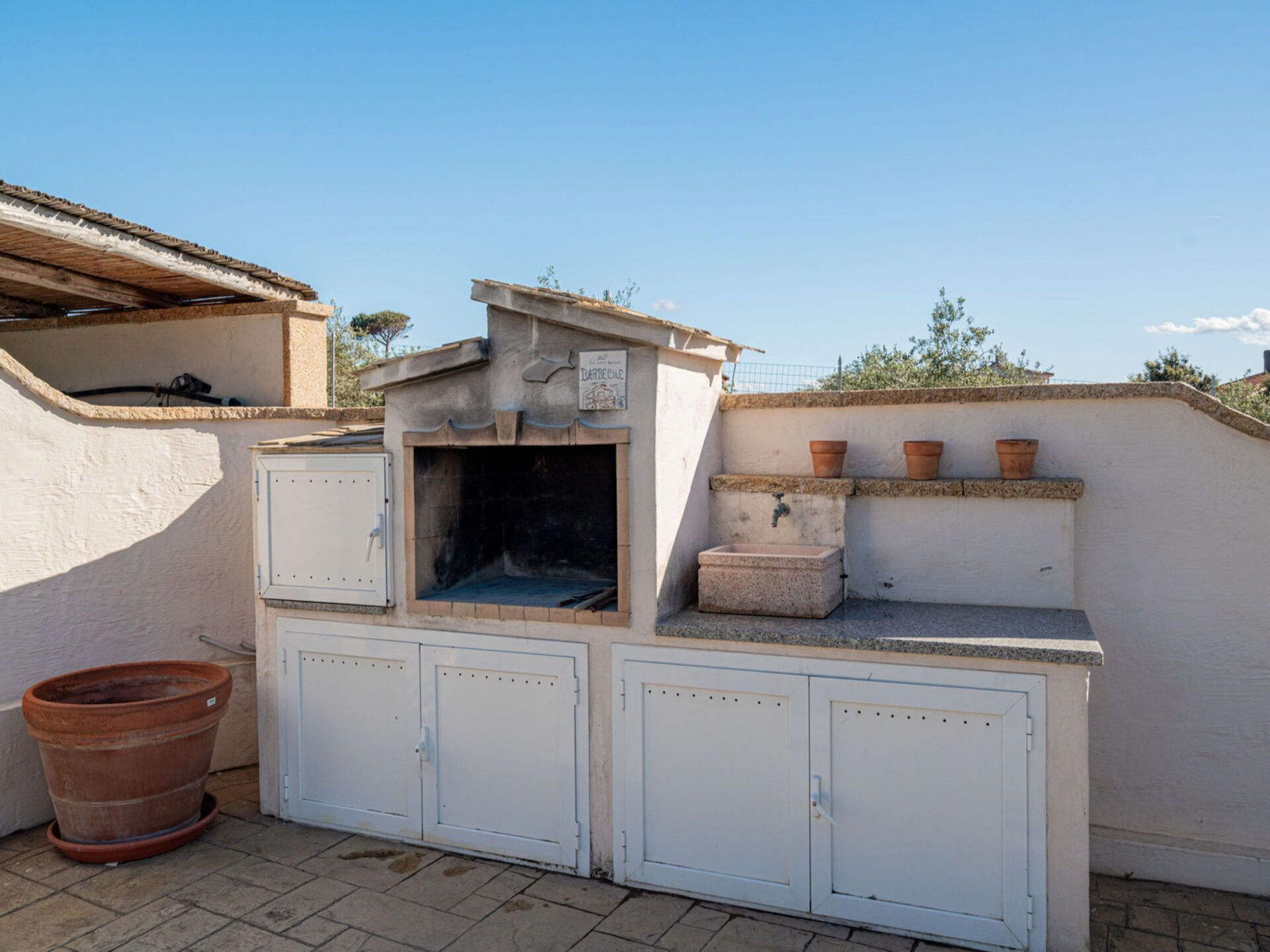 Zona de barbacoa con horno integrado, un lavadero y armarios de almacenamiento.