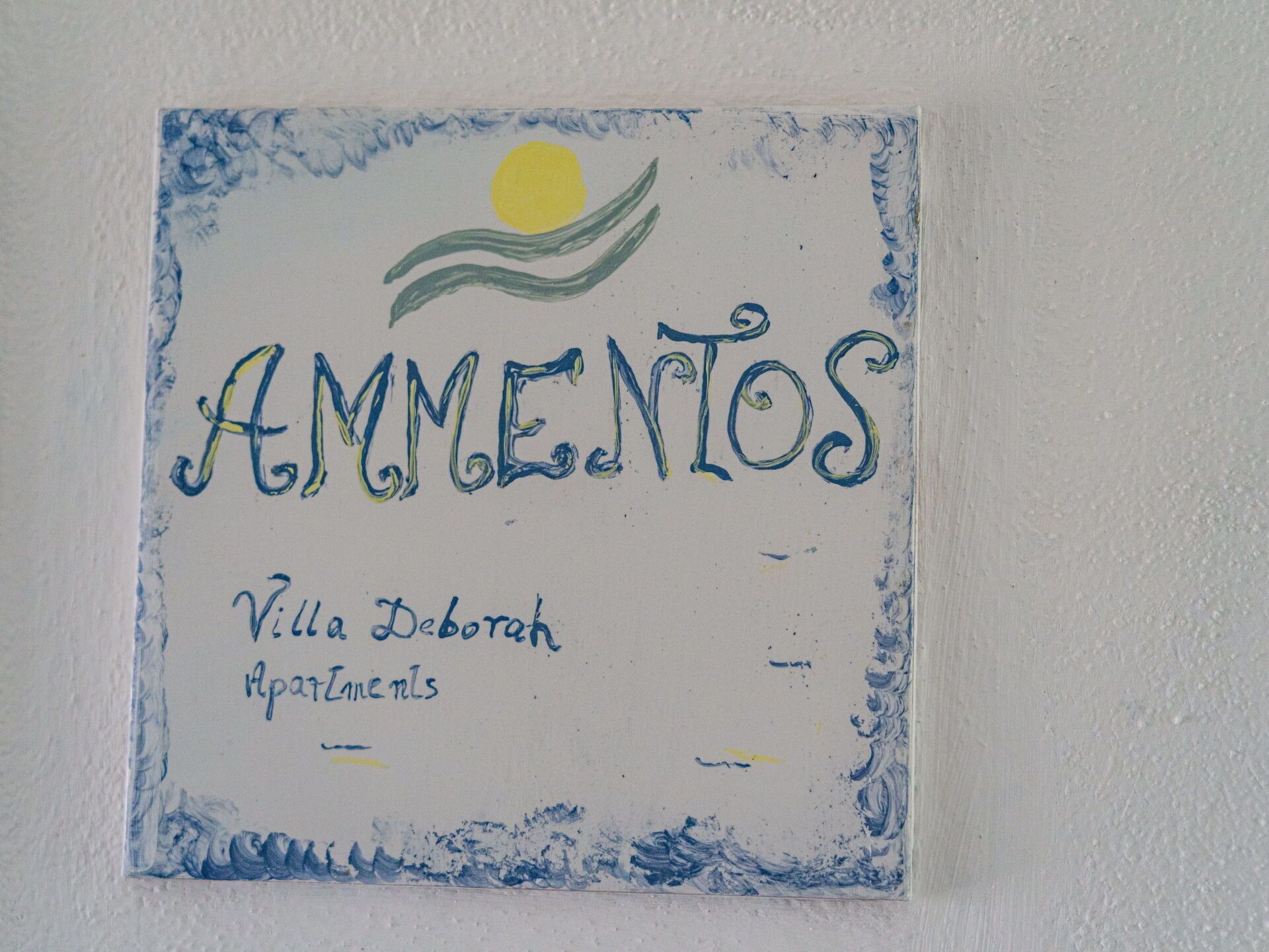 A sign with the text "AMNIENTOS" and "Villa Deborah Apartamentos" indicating a residential area or apartment complex.