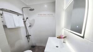A modern bathroom with a white sink, a toilet, and a shower with a handheld showerhead. - Kinh Bac Hotel (Ho Chi Minh City)