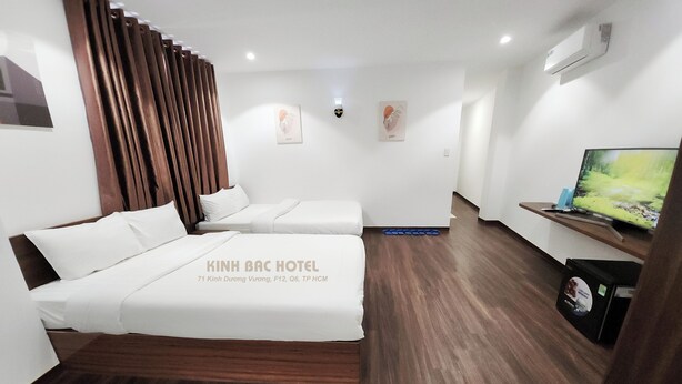 A hotel room with two beds, a TV, and a wooden floor. - Kinh Bac Hotel (Ho Chi Minh City)
