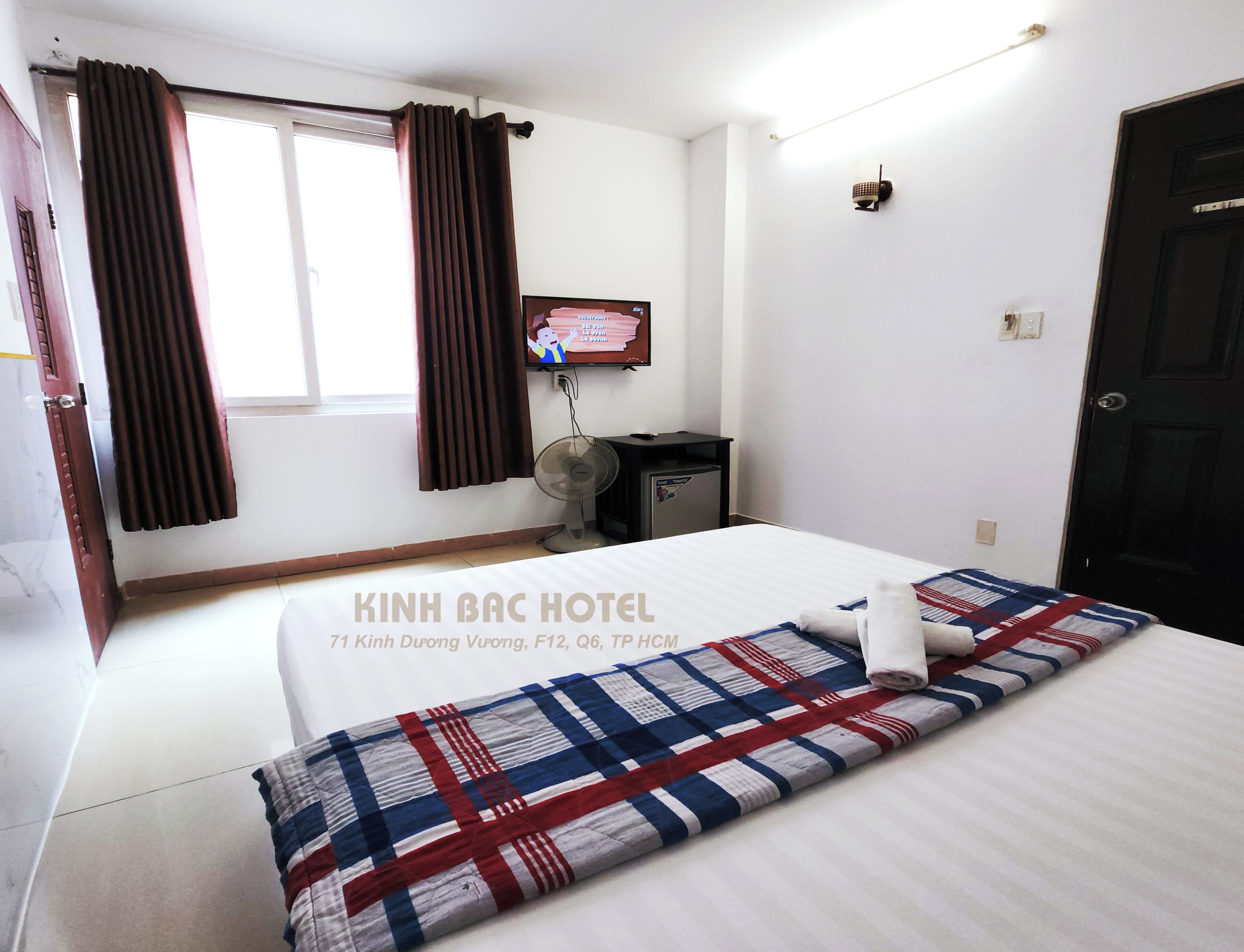 Une chambre d’hôtel avec un lit, une télévision, un bureau et une fenêtre avec des rideaux.