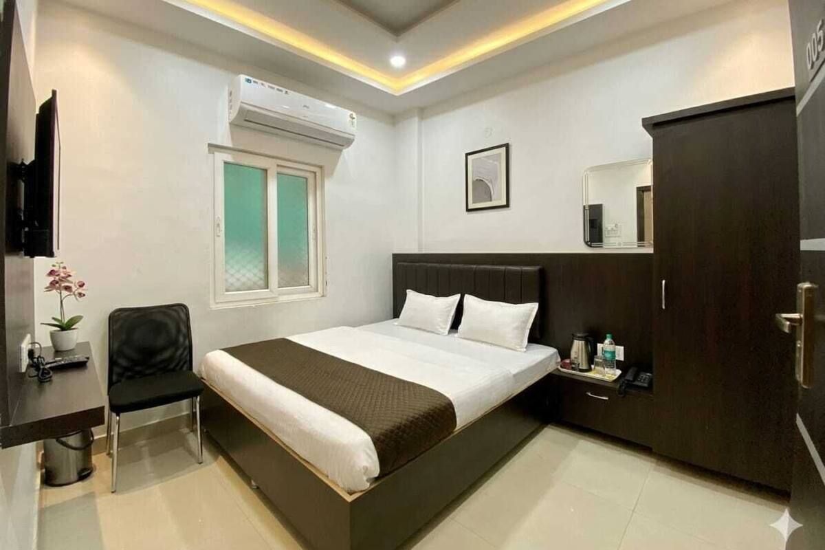 Habitación de hotel con cama, escritorio con silla, armario y unidad de aire acondicionado.