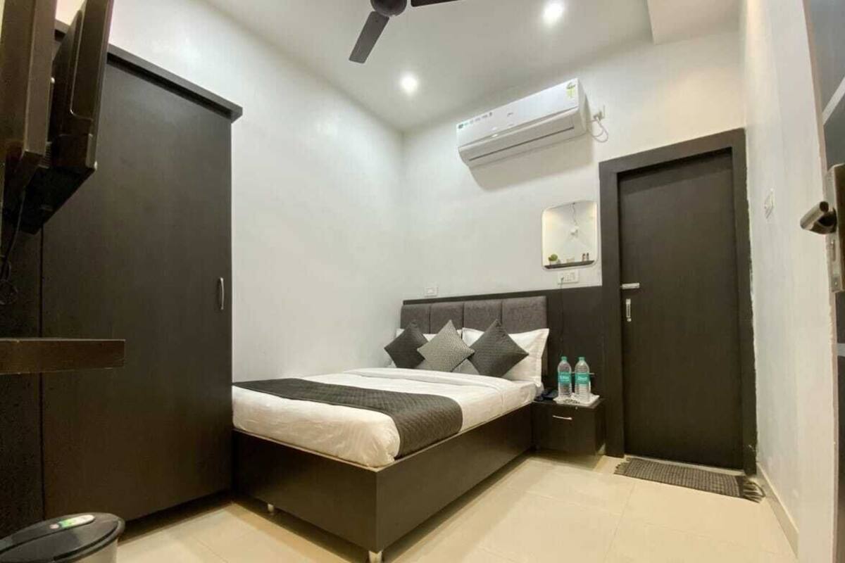 Un dormitorio con cama, mesita de noche, armario y unidad de aire acondicionado.