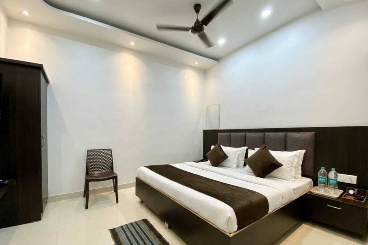 Una habitación de hotel moderna con cama, una silla, una mesita de noche y un ventilador de techo.