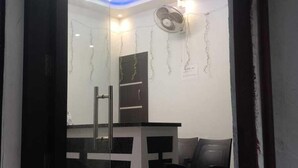Un comedor moderno con un panel de vidrio, un ventilador de techo y una lámpara de araña.