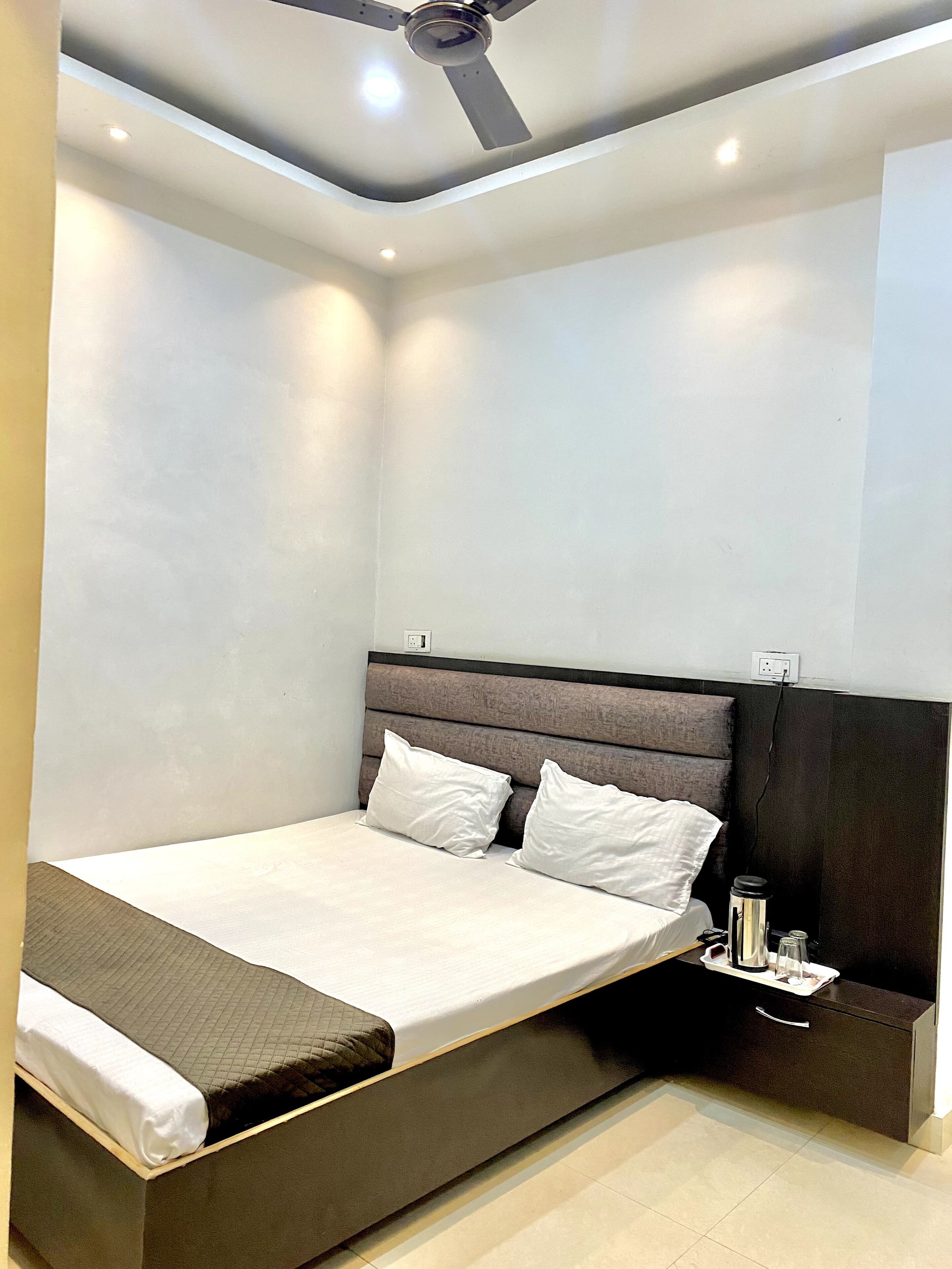 Een moderne slaapkamer met een bed, nachtkastje en plafondventilator.