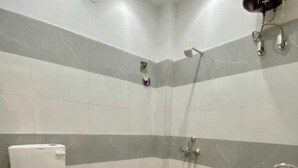 Un baño con inodoro, lavabo, ducha y un taburete pequeño.
