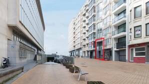 A modern urban street with buildings, a paved walkway, and a few parked bicycles. - Duplex Apartment, 50m From Beach (Ostend)