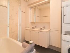A modern bathroom with a bathtub, double sink vanity, and a large mirror. - Duplex Apartment, 50m From Beach (Ostend)