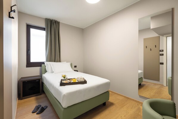A modern hotel room with a bed, bedside table, and a small desk. - ENERGY PARK HOTEL (Vimercate)
