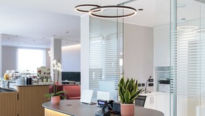 Een modern receptiebalie met een houten afwerking, een potorkidee en een laptop.