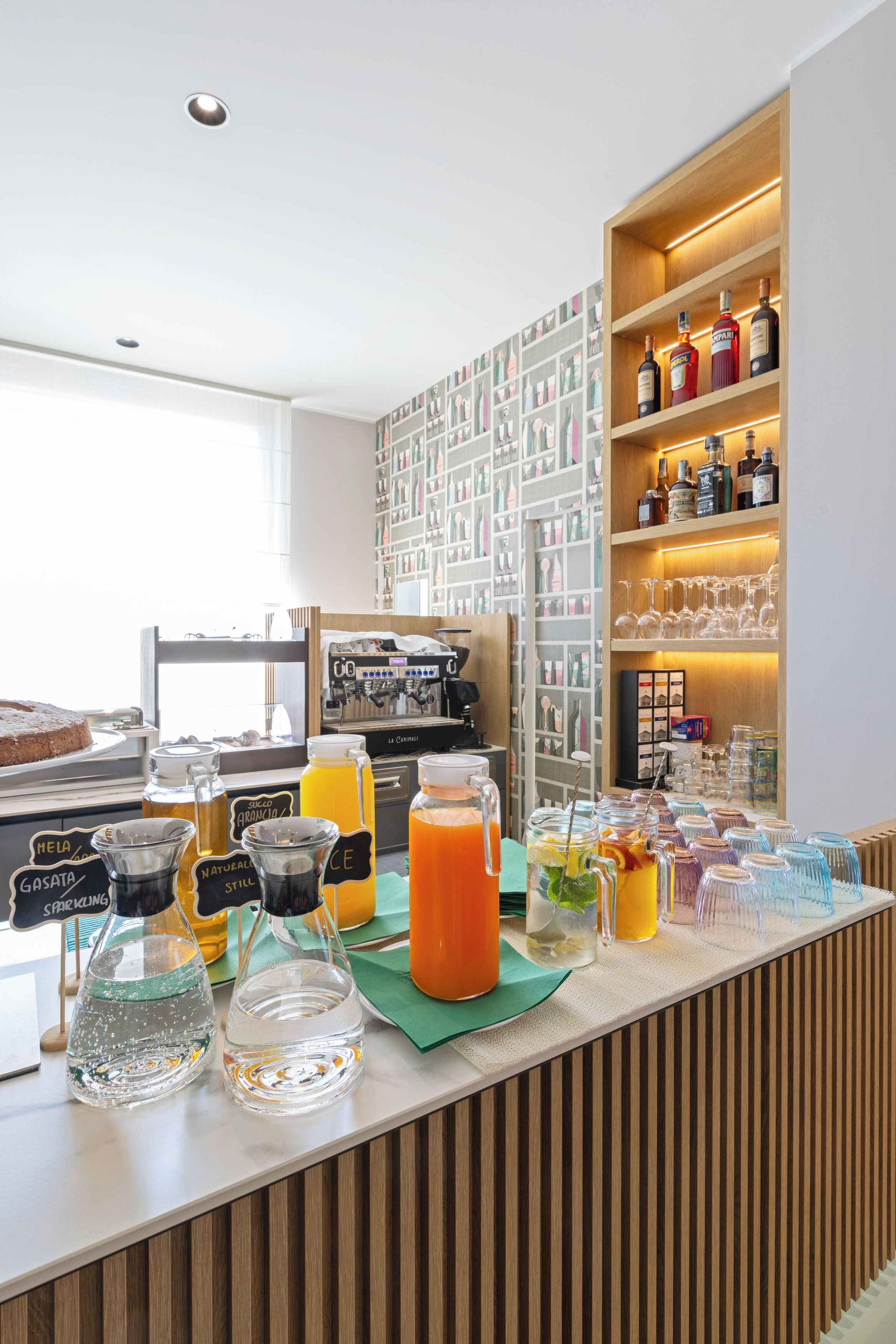 A breakfast bar with various beverages, a coffee machine, and a wall with framed pictures.