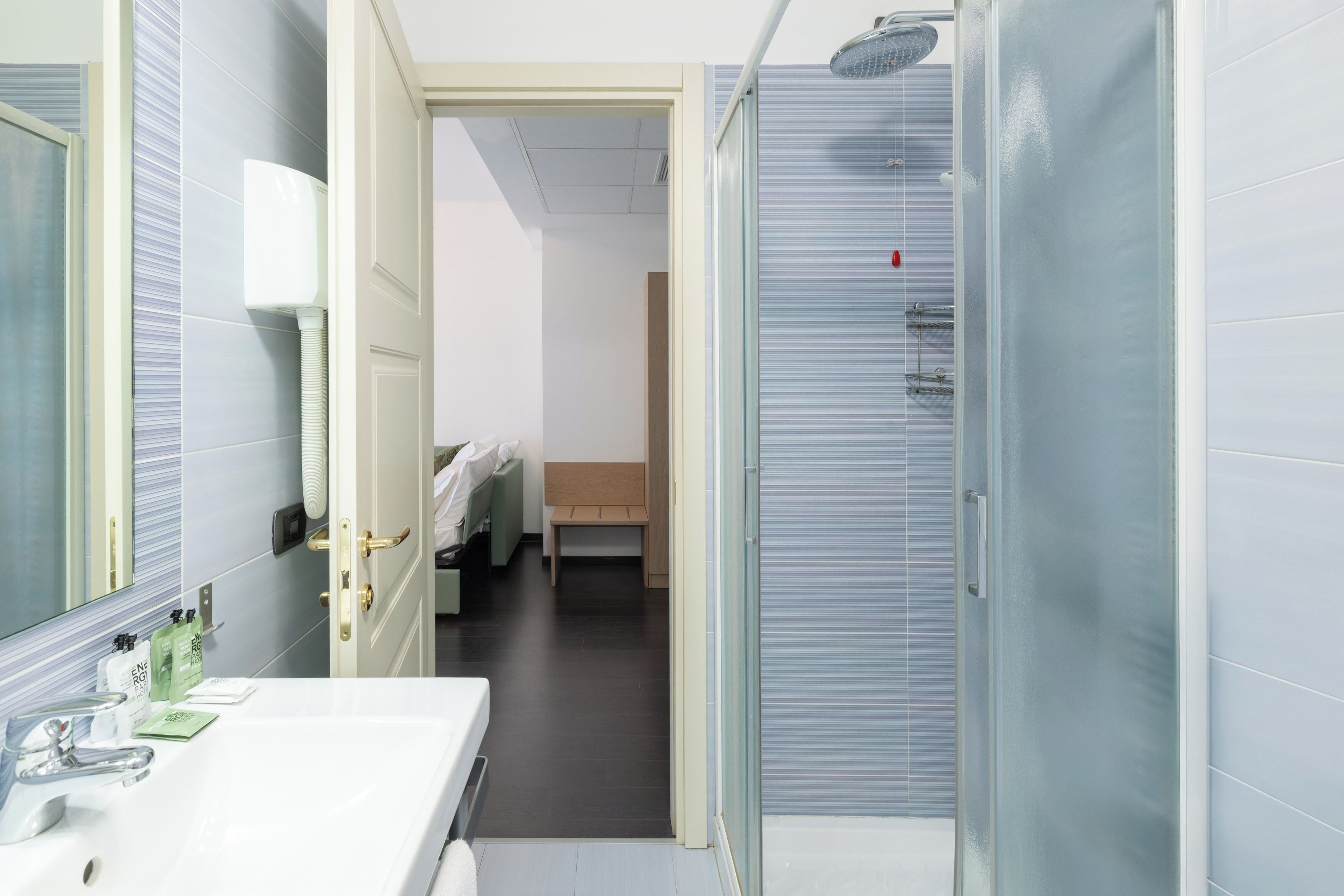 A modern bathroom with a white sink, a mirror, and a shower area.
