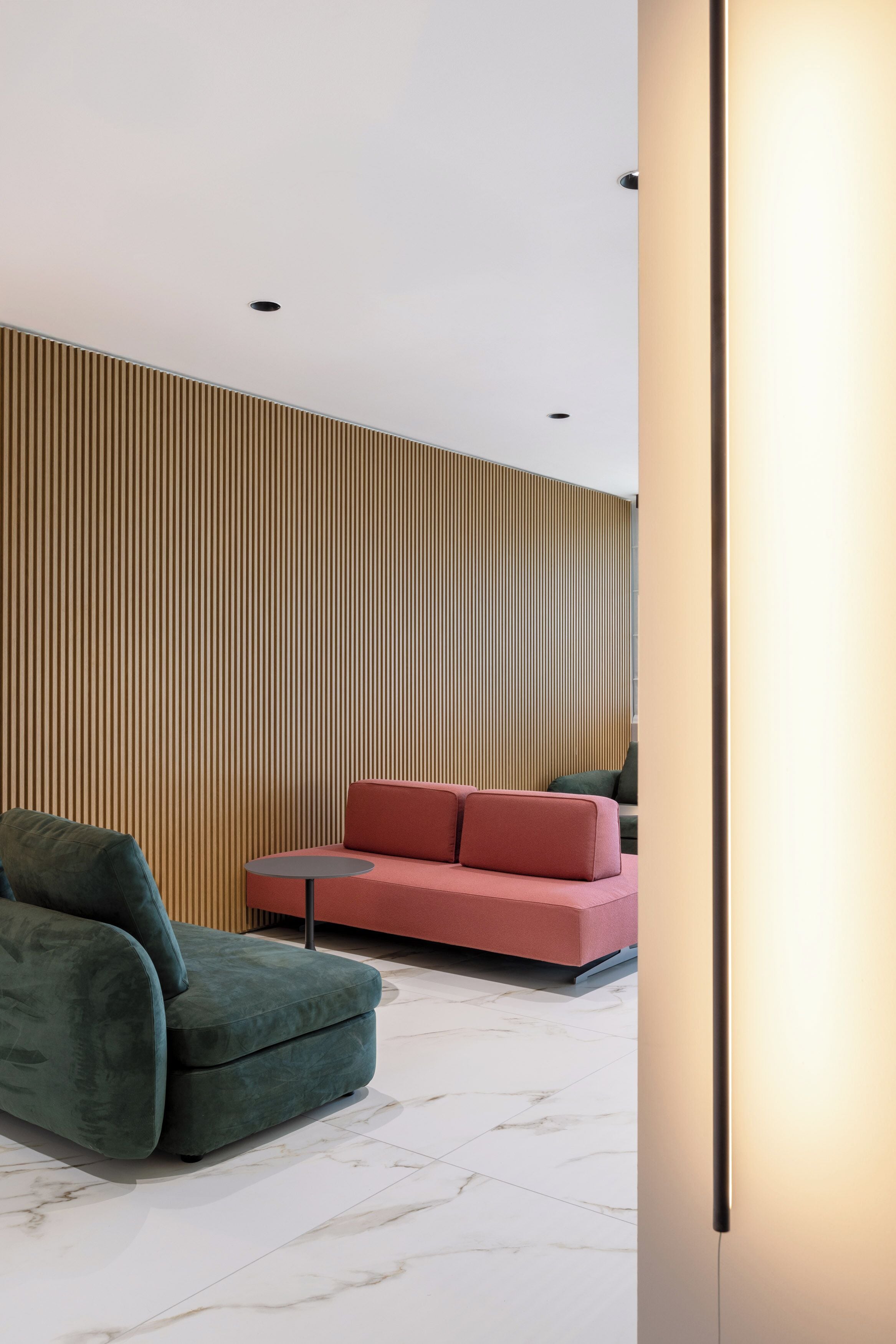 A modern interior with a sectional sofa, a green armchair, and a small round table.