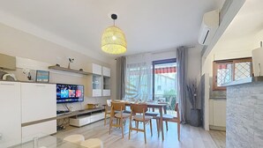 A modern kitchen with a dining area, a TV, and a large window with curtains. - Apt3BR,AC,WiFi, sea view, parking, 3min to beach (Fréjus)