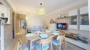 A modern dining area with a round table, chairs, and a television on the wall. - Apt3BR,AC,WiFi, sea view, parking, 3min to beach (Fréjus)