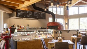 L’intérieur d’un restaurant, avec un décor en bois, une vitrine et un panneau affichant le menu.