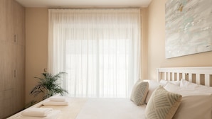 A bedroom with a bed, pillows, a bedside table, a plant, and a large window with sheer curtains. - Stone villa with private pool close to Marathi beach (Kounoupidiana, Marathi, Chania)