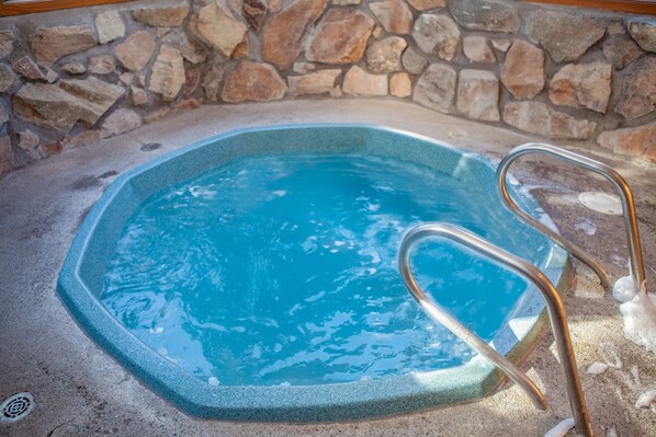 A hot tub with a stone wall background and metal ladder. - Walk to Main St & Trails | Hot Tub (Breckenridge)
