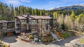 A multi-story building with a stone facade, multiple balconies, and a view of a mountainous landscape.