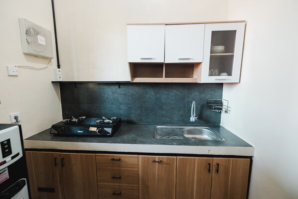 Una cocina compacta con estufa a gas, un lavabo y armarios de madera.