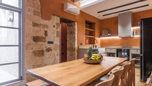 A kitchen with a wooden table, chairs, and a fruit bowl. - It's ideal for families
or groups of up to seven people. (Chania)