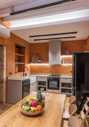 Enjoy meals at the kitchen's central island, where a bowl of fresh fruits and a wine glass await.
