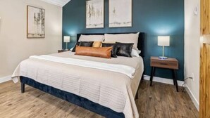A bedroom with a bed, wooden floor, and a sloped ceiling. - The Creekside Pump House (Spearfish)