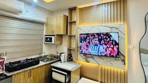 A modern kitchen with a built-in stove, microwave, and a TV mounted on the wall displaying a sports event. - Studio(S9)@LEKKI PHASE 1, 24/7 Pwr by NgoZiLiving

 (Lekki)