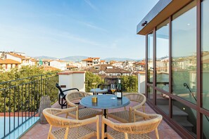 A balcony with wicker furniture, a table, and a bottle of wine. - This Time Tomorrow in Florence (Florence)