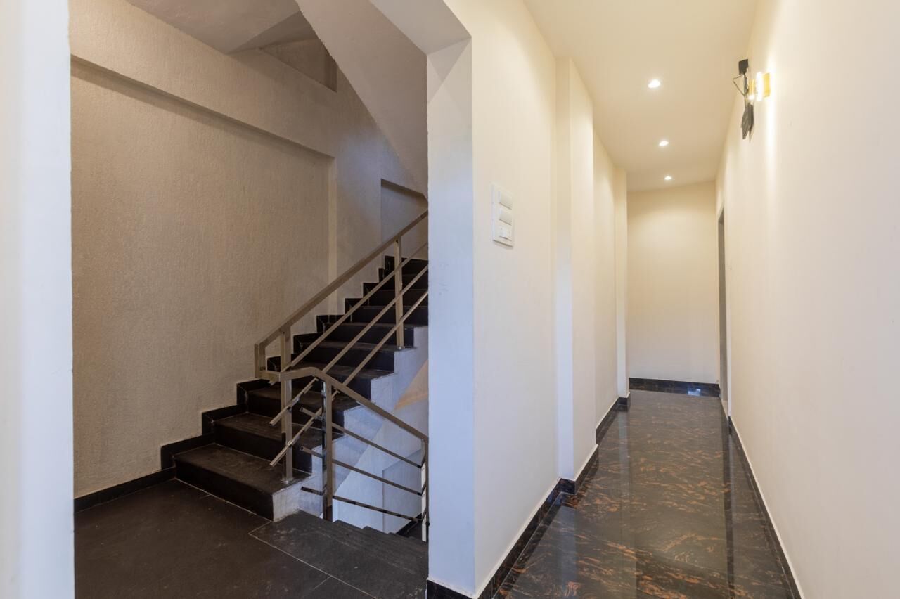 Un pasillo moderno de hotel con una escalera, suelo de mármol e iluminación empotrada.