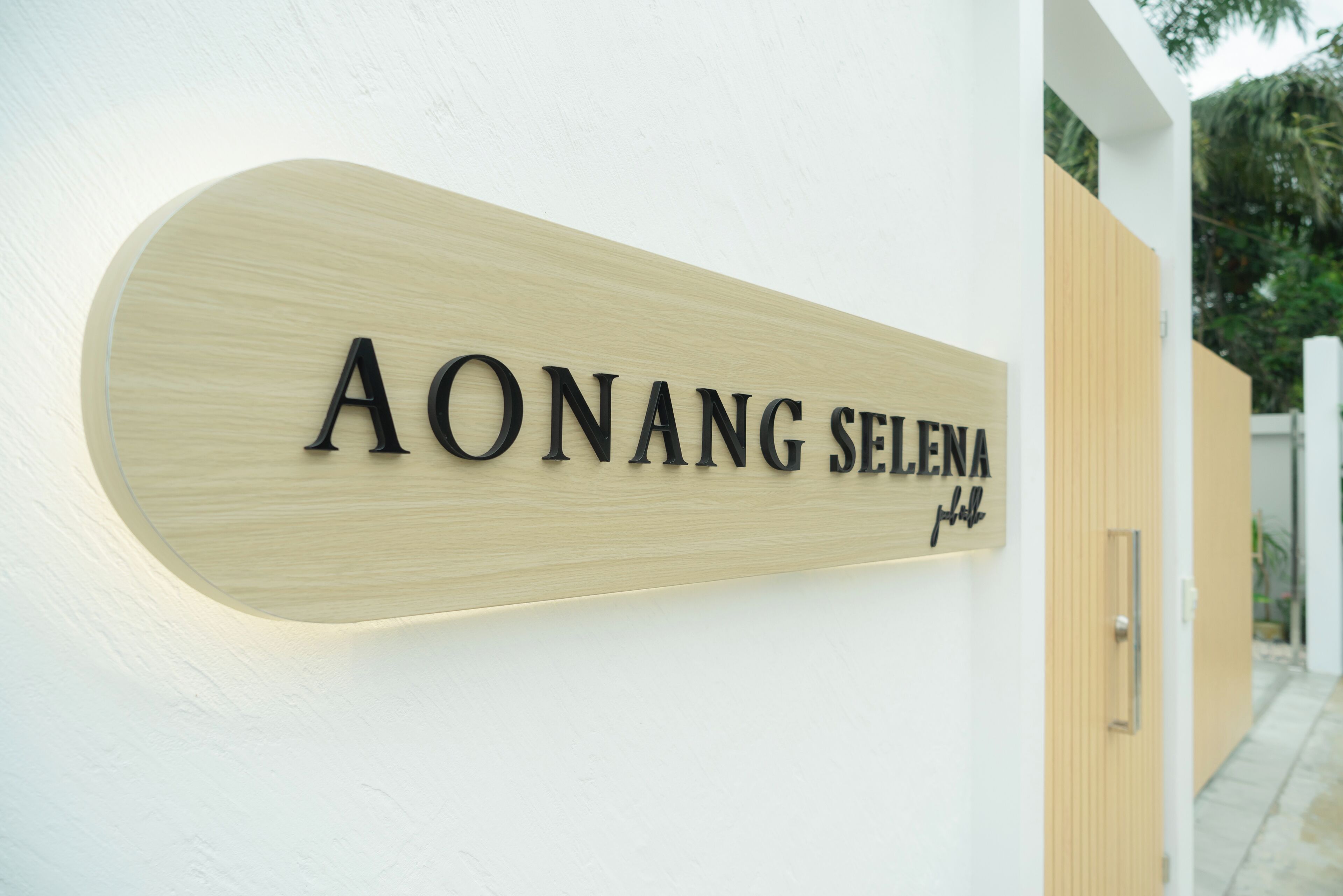 A wooden sign with the text "AONANG SELENA" on a white wall.