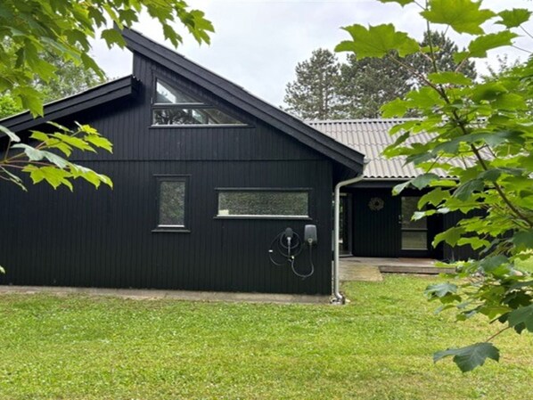 Un bâtiment noir avec un toit en pente, une petite fenêtre et une porte.