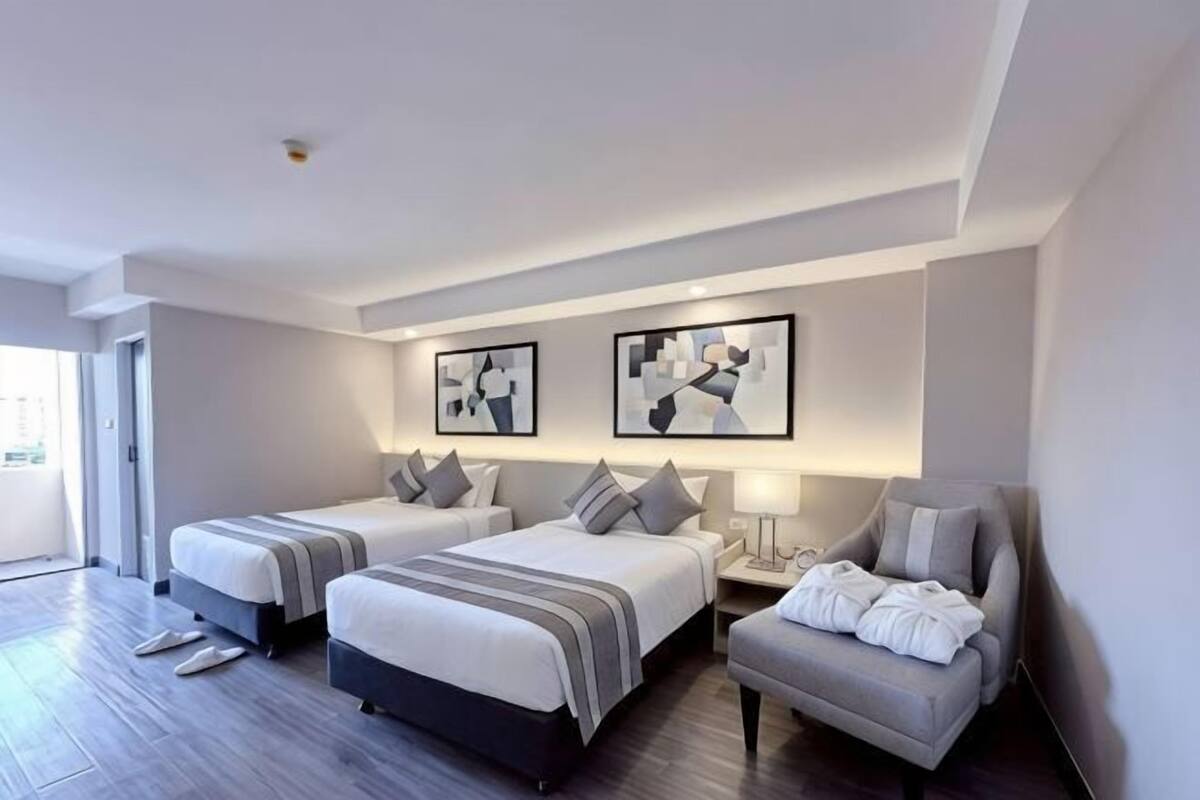 Une chambre d’hôtel avec deux lits, un canapé, un bureau et des œuvres d’art accrochées au mur.