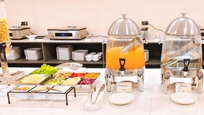 A buffet setup with various food options and a fruit juice station.