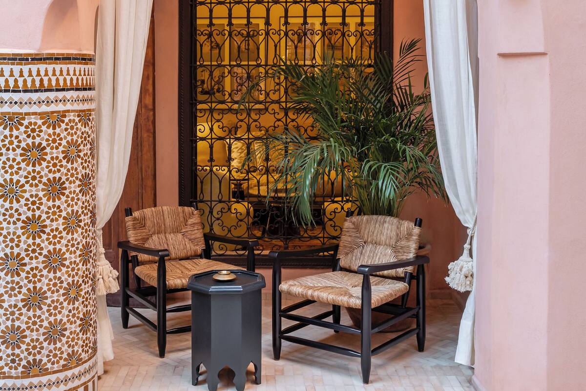 An arched entrance with a patterned curtain, a wicker chair, a small table, and a hanging light fixture.