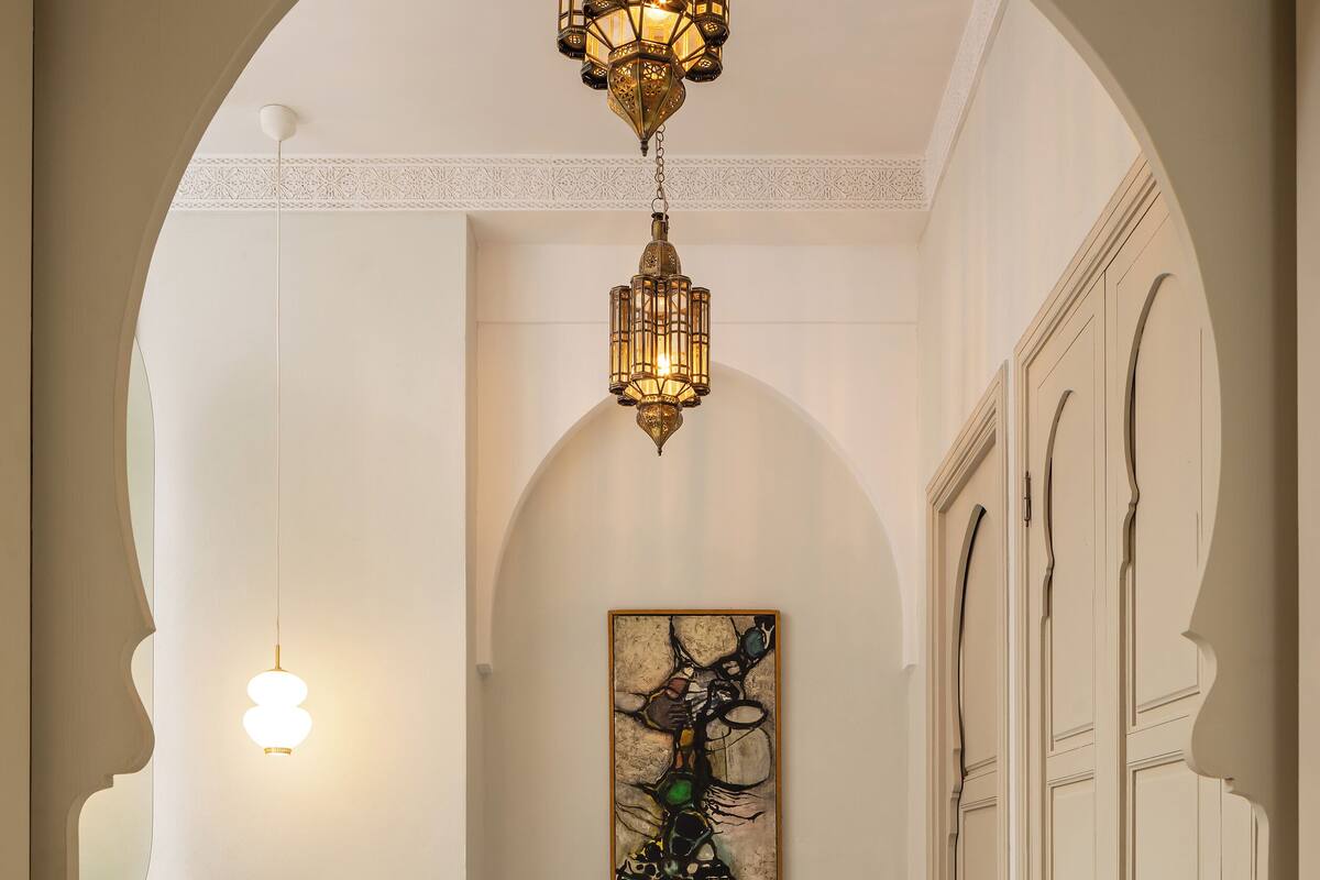 A hallway with a geometric patterned floor, a marble-topped sink, a hanging light fixture, and a painting on the wall.