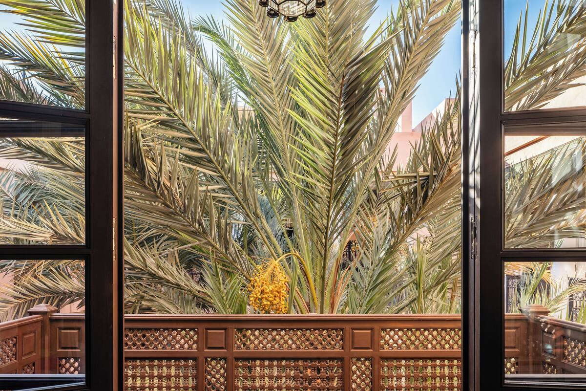 A balcony with a view of palm trees, a patterned fence, and wicker furniture.