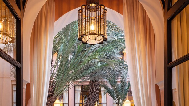 An indoor atrium with a palm tree, a chandelier, and a dining area. - This Time Tomorrow in Marrakech (Marrakech)