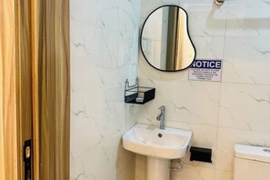 A bathroom with a white sink, a mirror, and a toilet. There is a notice on the wall advising not to flush paper towels or sanitary products down the toilet. - Studio(S8)@LEKKI PHASE 1, 24/7 Pwr by NgoZiLiving


 (Lekki)
